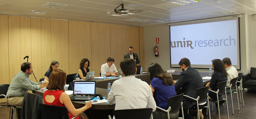 personas reunidas alrededor de una mesa con una pantalla de unir research